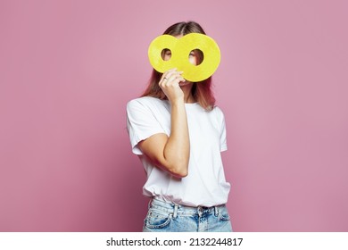 Pretty woman hiding her face behind yellow number eight 8 banner on pink background. Young model in white blank t-shirt