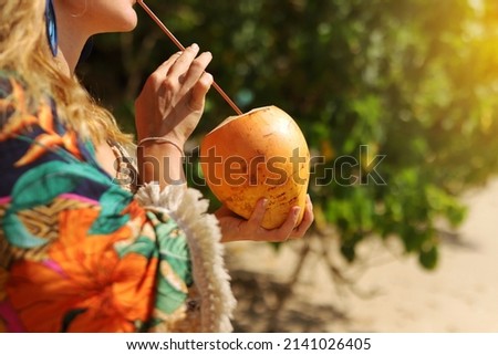 Pretty woman holding a coconut in tropic  background.Close up.Tropic concept.Space for text