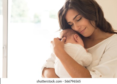 Красивая женщина держит новорожденного ребенка на руках