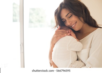 Pretty Woman Holding A Newborn Baby In Her Arms