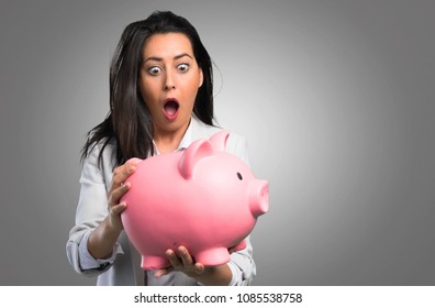 Pretty woman holding a piggybank on grey background