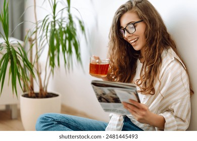 Pretty woman at home drinking tea and reading book or magazine. Domestic life. - Powered by Shutterstock