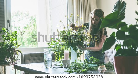 Woman makes wildflower bouquet in vase on the table