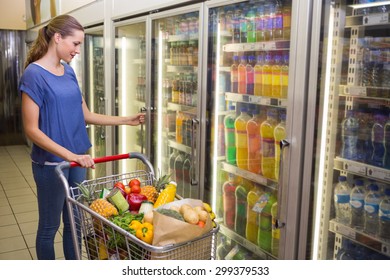 Pretty Woman Looking At Camera And Taking Product On Pretty Woman Taking Botlte Of Water In Freezer At Supermarket