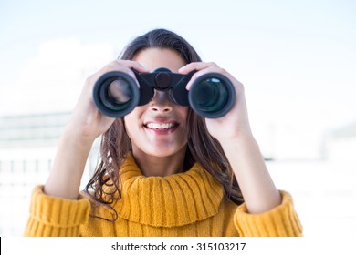 Pretty woman looking through binoculars outside