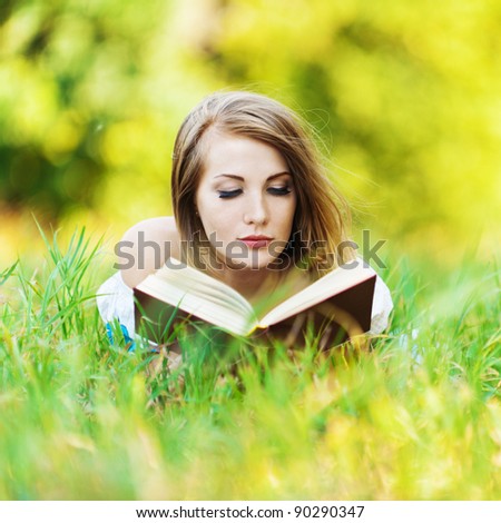 pretty woman lying clearing grass reading book