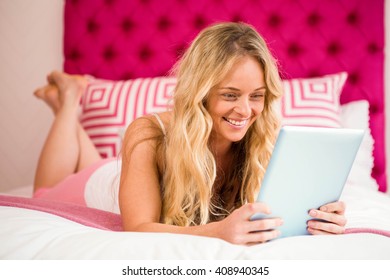 Pretty Woman Lying On Her Bed Using Tablet In The Bedroom