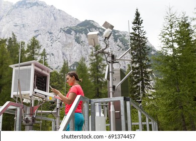 Pretty woman meteorologist reading meteodata instruments in modern meteorologic observation station, high in mountains