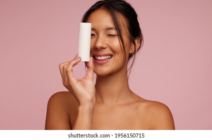 Pretty Woman Model Holding A Cosmetic Bottle And Smiling. Playful Asian Female With New Skincare Product.