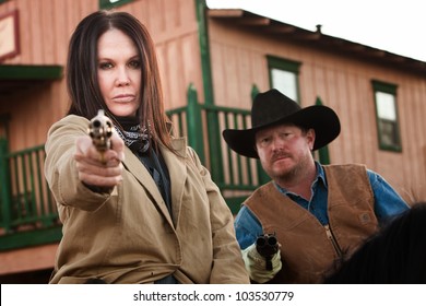 Pretty Woman And Partner Aim Guns In Old West Town