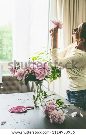 Woman with peonies on table in the living room