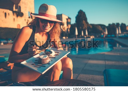 Pretty Woman With Pleasure Eating Tasty Sweet Dessert near the Pool on the Beach Resort. Enjoying Happy Active Summer Vacation.