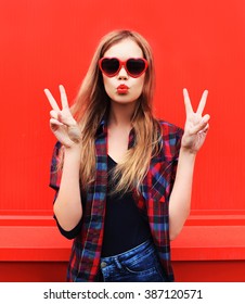 Pretty Woman In Red Sunglasses Blowing Lips Kiss Over Colorful Background