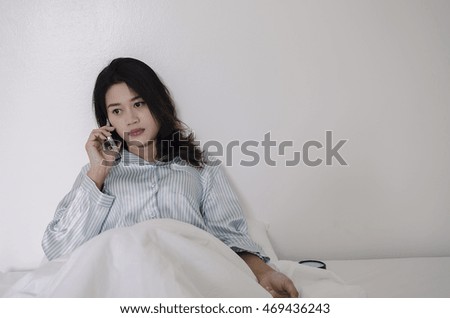 The pretty woman in the room talking on smartphone on the bed.