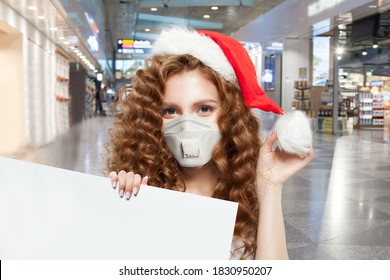 Pretty Woman Santa In Protective Medical Mask Holding Empty Signboard In Shopping Mall. Christmas And New Year Sale Concept