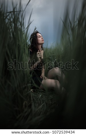 beautiful young woman siiting outdoors in forest, dreaming with closed eyes in serene pose