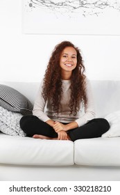 Pretty Woman Sitting On Sofa In Front Of White Background