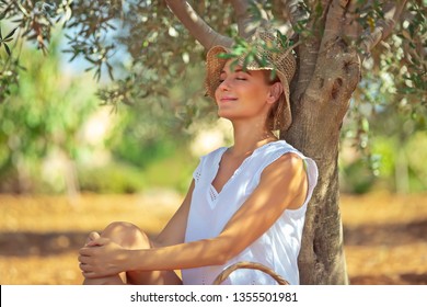 Pretty woman sitting and resting under the tree in the garden, enjoying nice warm spring day, spending leisure time outdoors, happy spring holidays - Powered by Shutterstock