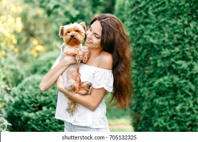 pretty woman smiling beautiful young happy with long dark hair in white dress holding small dog puppy yorkshire terrier - Powered by Shutterstock