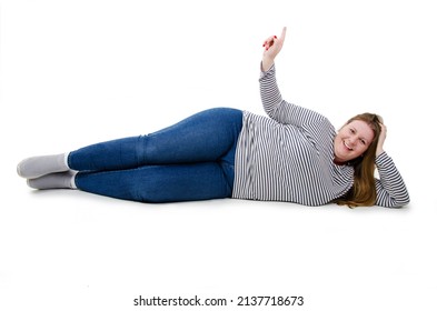 Pretty woman smiling with happy face pointing up with finger. Laughing plus size woman lying on floor showing direction looking at camera. Joyful overweight woman. Isolated on white background