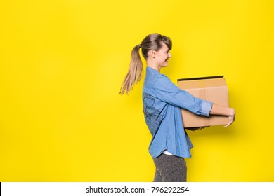 pretty woman standing on yellow background with moving cardboard box
