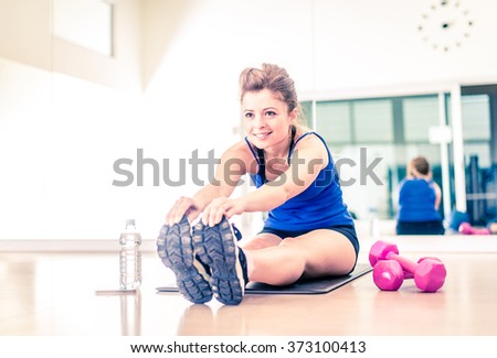 Pretty woman stretching in a fitness club - Young beautiful girl warming up for a workout session