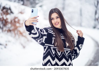 Pretty woman take a selfie with smartphone at winter outside - Powered by Shutterstock