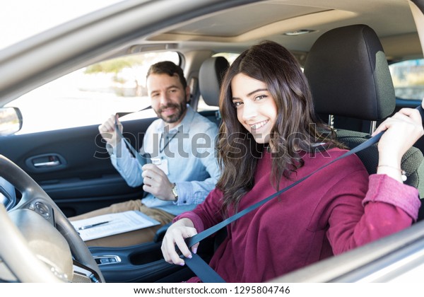 Pretty woman taking life saving driving tips from\
instructor while sitting in\
car
