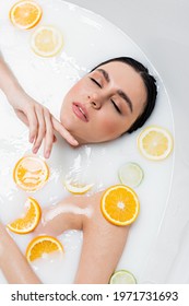 Pretty Woman Touching Chin While Taking Milk Bath With Citrus Slices