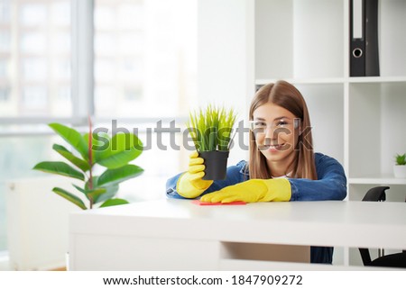 Pretty woman in uniform with supplies cleaning in office