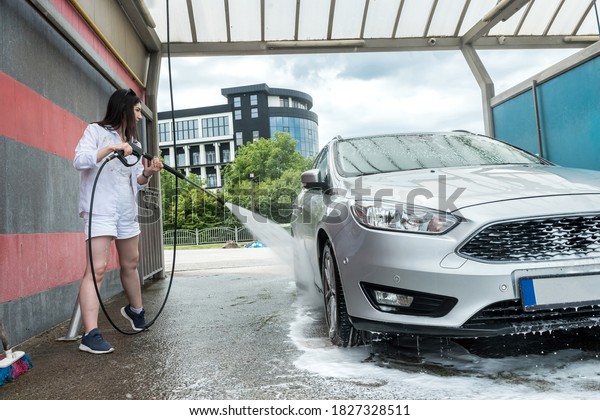 Pretty woman washing \
and car cleaning with foam and pressured water. Concept for\
cleaning or care car. 