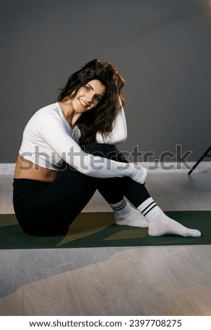 Pretty woman in white sportswear doing morning exercises on the mat and doing yoga