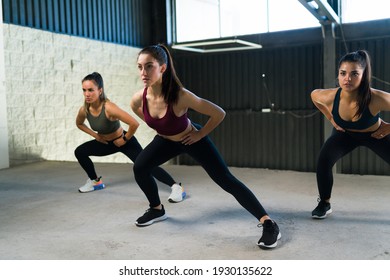 Pretty Women Exercising And Doing Hip Openers. Caucasian Women With A Healthy Lifestyle During A HIIT Class At The Gym