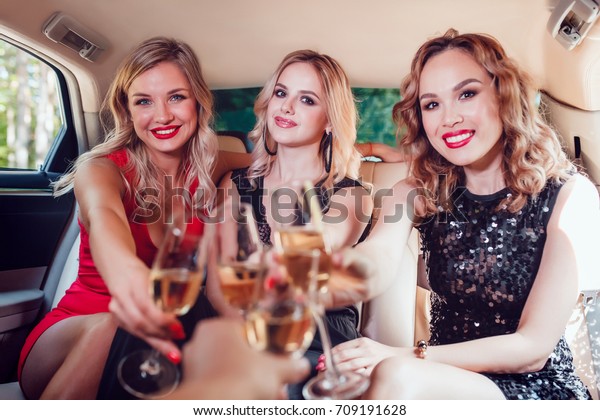Pretty women having party in a limousine car
and drinking champagne.