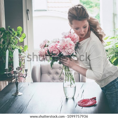 Similar – Woman with peonies on table in the living room