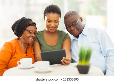 pretty young adult african girl with senior parents using tablet computer