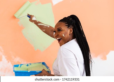 Pretty young african american woman with painting roller indoors. Redecoration, renovation, apartment repair and refreshment concept. - Powered by Shutterstock