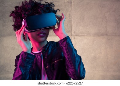 Pretty young African girl adjusting the VR headset on the white background