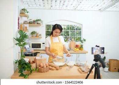 Pretty young asian female food blogger working on a new video and explaining how to cook a dish - Powered by Shutterstock