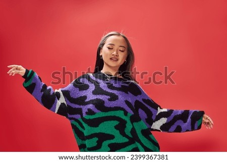 pretty young asian girl in vibrant sweater with animal print with heart shaped necklace on red, ease