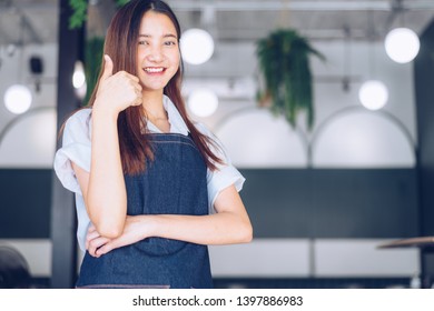Pretty young asian waitress standing arms crossed in cafeteria.Coffee Business owner Concept.  barista in apron smiling at camera in coffee shop counter - Shutterstock ID 1397886983