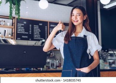 Pretty young asian waitress standing arms crossed in cafeteria.Coffee Business owner Concept.  barista in apron smiling at camera in coffee shop counter - Shutterstock ID 1418035745
