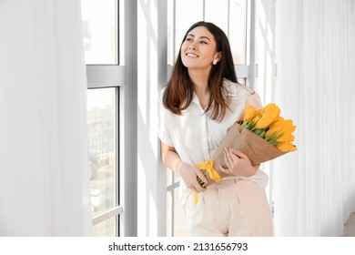 Pretty Young Asian Woman With Bouquet Of Flowers Near Window