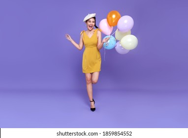 Pretty Young Asian Woman At Celebration Party Holding Colourful Balloon Running And Smile Face. Happy New Year Or Birthday Eve Celebrating Concept On Bright Purple Background.