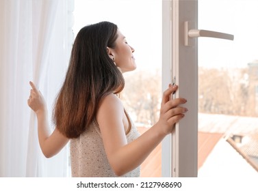 Pretty Young Asian Woman Opening Window At Home