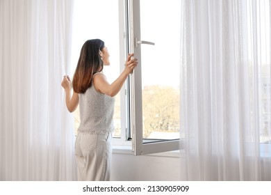 Pretty Young Asian Woman Opening Window At Home