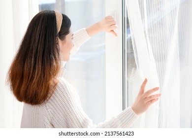 Pretty Young Asian Woman Opening Window At Home