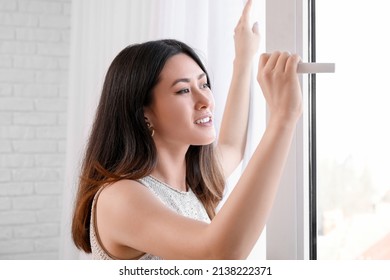 Pretty Young Asian Woman Opening Window At Home