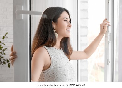 Pretty Young Asian Woman Opening Window At Home