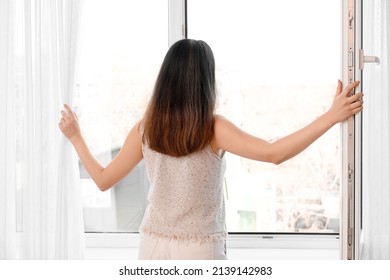 Pretty Young Asian Woman Opening Window At Home